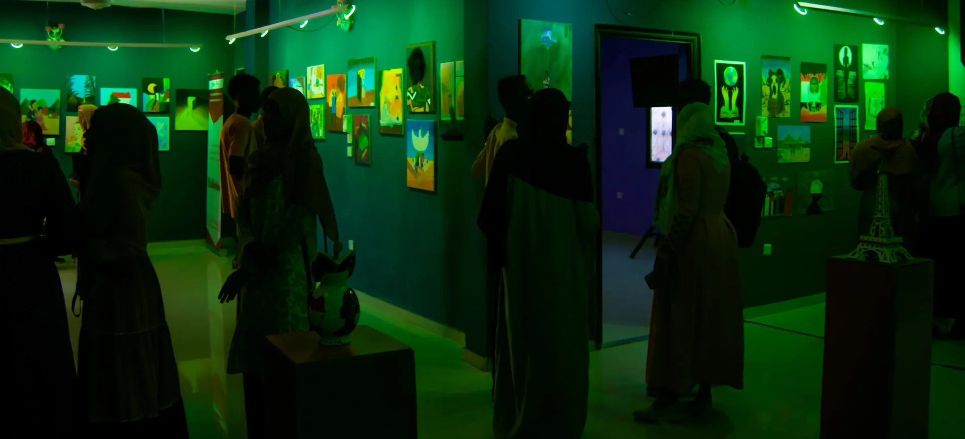 Visitors viewing paintings at a G.Artistic art exhibition.